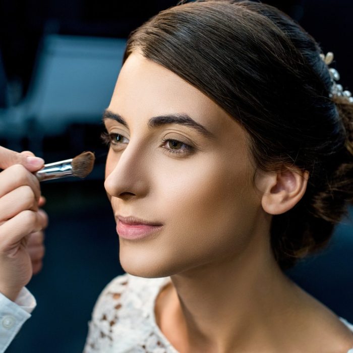 portrait-of-young-woman-getting-makeup-done-by-makeup-artist.jpg